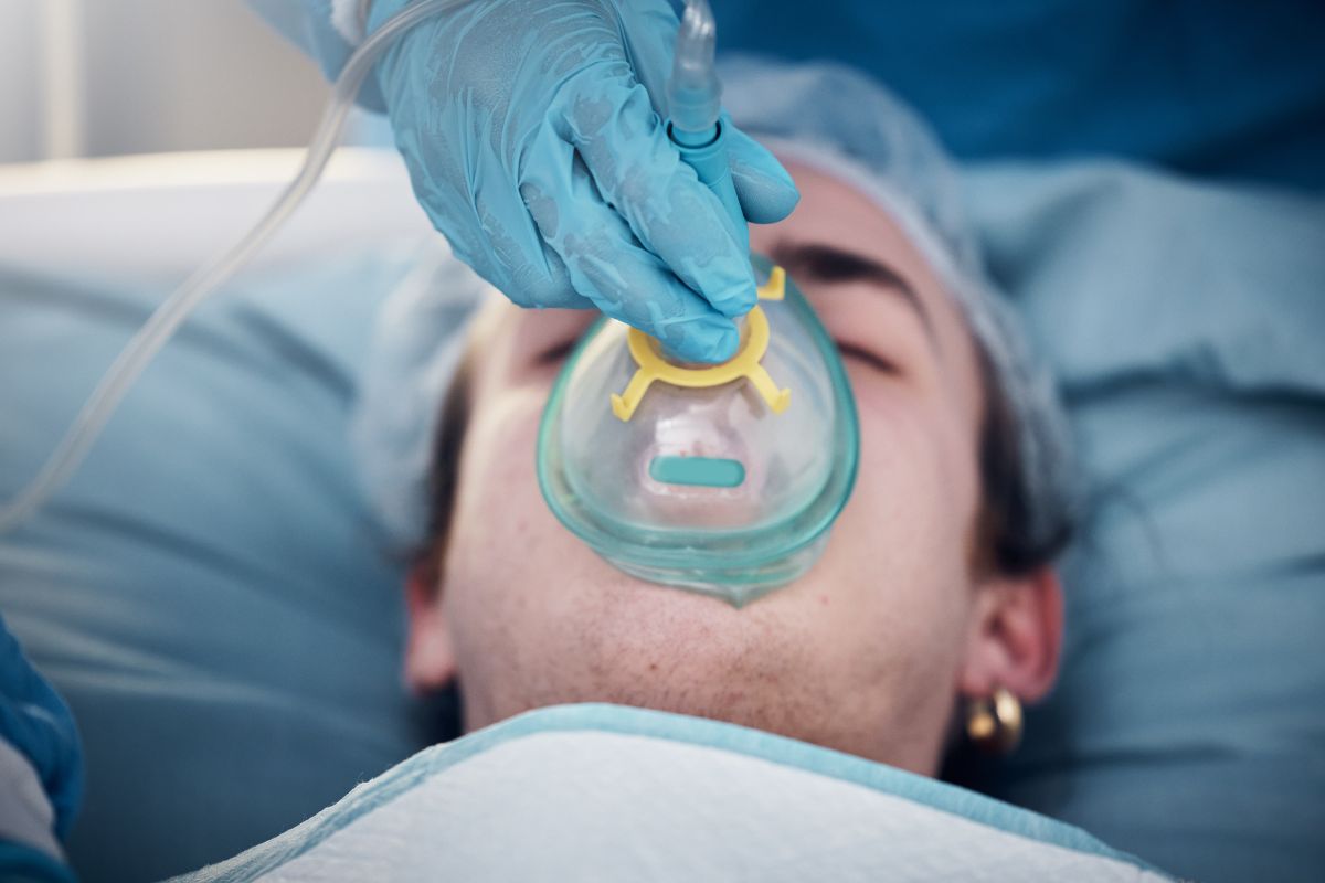 Patient receiving emergency dental treatment with oxygen mask and clinical support during a same-day dental visit for urgent care